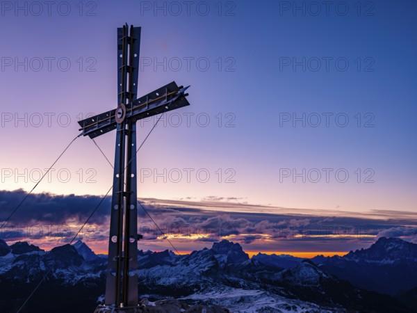 Sassongher summit cross at dawn, in the background Monte Cristallo, Monte Pelmo and Civatta, Dolomites, Trentino, South Tyrol, Italy