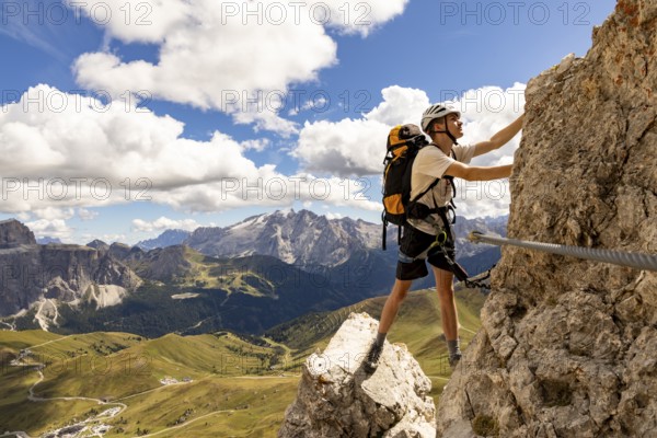 Mountaineer climbs on Ferrata Furcela de Saslonch, Langkofelscharte via ferrata, Dolomites, Trentino, South Tyrol, Italy