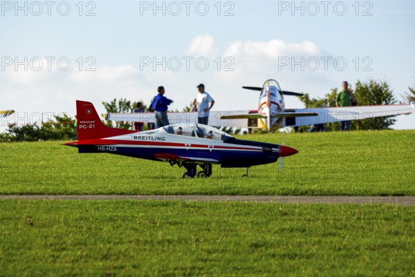 An RC model of a Pilatus PC-21 with advertising for the Swiss watch brand Breitling during a flight demonstration as part of an air show at the Rossfeld in Metzingen-Glems, Baden-Württemberg, Germany, for editorial use only