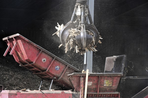 Loading crane with grab arm for loading wood waste for wood pellet production on the premises of Energie-Mann in the Westerwald. manufactured