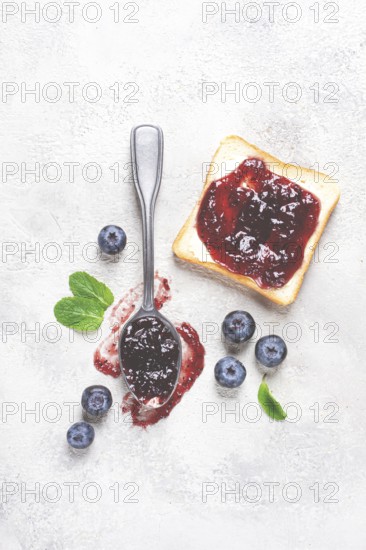 A spoon with blueberry jam, on a white table, breakfast, top view, homemade, no people