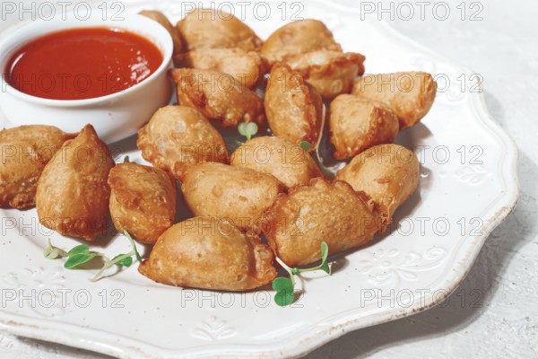 Fried mini chebureks, with sauce, on a decorative plate, hard light, no people