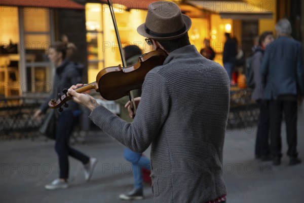 Italy, street musician entertaining tourists near landmark Florence attraction of Il Duomo cathedral. Street musician playing violin