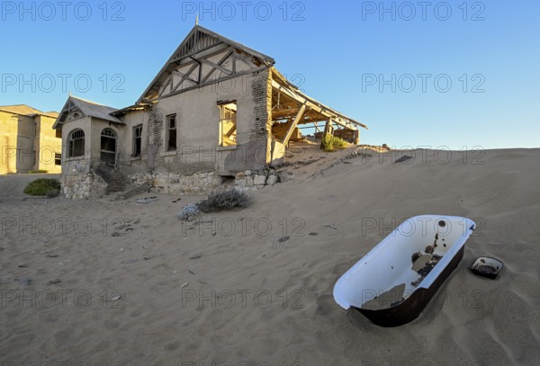 Bathtub in the sand in front of a former dwelling house, Kolmanskop, restricted diamond area, Karas region, Namibia