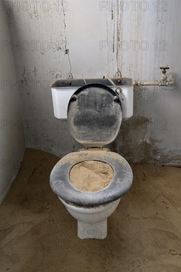 Toilet full of sand in the former hospital, Kolmanskop, restricted diamond area, Karas region, Namibia