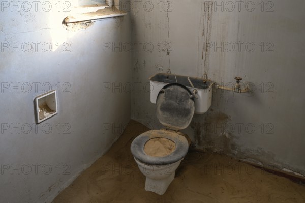 Toilet full of sand in the former hospital, Kolmanskop, restricted diamond area, Karas region, Namibia
