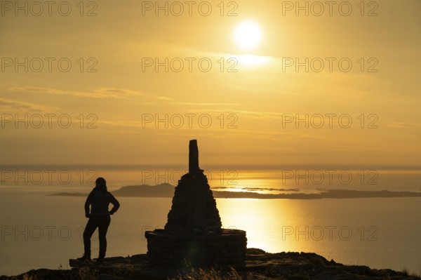 Woman standing next to cairn and looking at the sea, Rørsethornet stone staircase, with 3292 steps one of the longest continuous stone staircases in the world, Sherpat stairs or Midsund stairs or Midsundtrappene, Rørsethornet hike, evening mood, Otroya or Otrøya island, Møre og Romsdal, Norway