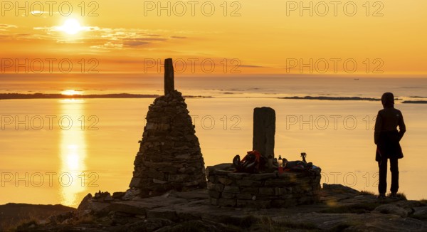 Silhouette of a woman watching the sunset next to cairns, Rørsethornet stone staircase, with 3292 steps one of the longest continuous stone staircases in the world, Sherpatreppe or Midsundtreppe or Midsundtrappene, Rørsethornet hike, Otroya or Otrøya island, Møre og Romsdal, Norway