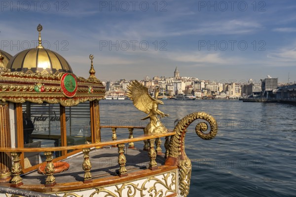 Golden oriental restaurant ship on the banks of Eminönü, Beyoglu and the Galata Tower, Istanbul, Turkey