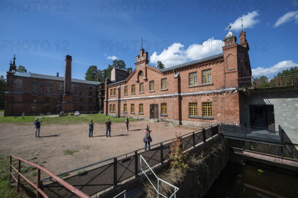 Visitors in front of the former paper mill and groundwood pulp board mill, UNESCO World Heritage Site Verla Factory Village, Maailmanperintökohde Verlan puuhiomo ja pahvitehdas, Verla Rapids, Kymenlaakso, near Kouvola, Finland