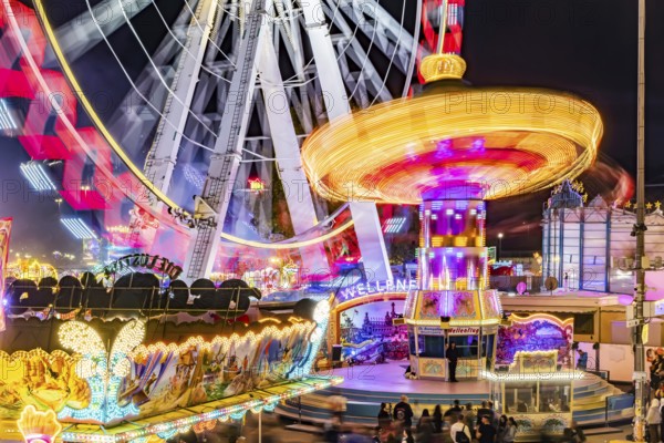 Folk festival in Stuttgart. The 178th Cannstatter Volksfest on the Wasen is one of the most important traditional festivals in Germany. Ferris wheel, chain carousel and other amusement park attractions, light effects at night. Stuttgart, Baden-Württemberg, Germany