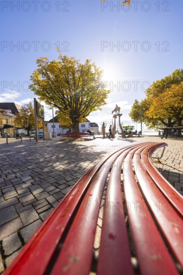 Red benches on a sunny town square surrounded by autumnal trees, Überlingen, Lake Constance, Germany