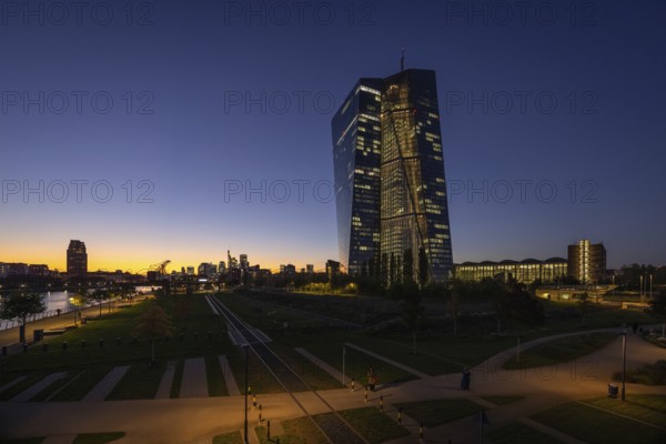 The lights of the European Central Bank (ECB) and the Frankfurt banking skyline glow in the evening, Frankfurt am Main, Hesse, Germany