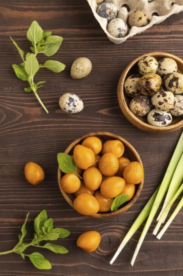 Pile of Smoked Quail eggs in bowl on a brown wooden background. top view, flat lay, close up