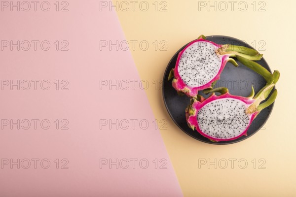 Ripe Pitaya on blue plate on pink and orange pastel paper background, top view, flat lay, copy space, minimalism