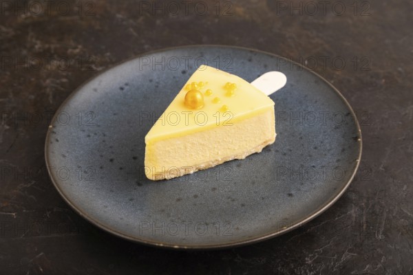 Yellow Cake pop with sprinkles on blue ceramic plate on black concrete background, side view, close up, minimalism