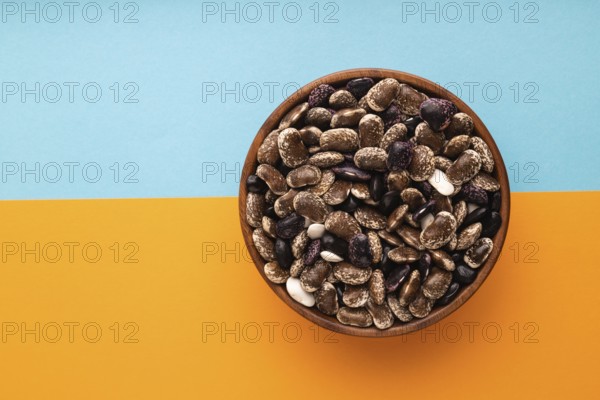 Wooden bowl with Kidney beans on blue and orange pastel paper background, top view, flat lay, copy space, minimalism