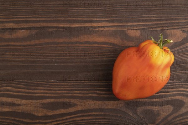Red Heart Shape tomato on brown wooden background. Top view, flat lay, copy space. healthy food, vegetable, minimalism