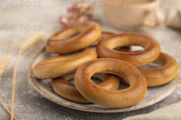 Homemade Ring Bagel with cup of coffee on brown concrete background and linen textile. side view, close up, selective focus