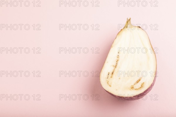 Purple Cutted eggplant with white stripes on pink pastel background. Side view, copy space. Tropical, healthy food, vegetable, slice, minimalism