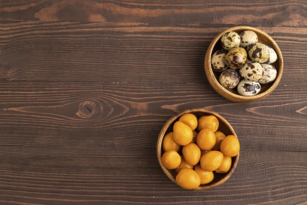 Pile of Smoked Quail eggs in bowl on a brown wooden background. top view, flat lay, copy space