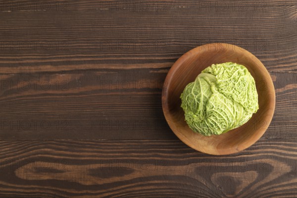Green lettuce on plate on brown wooden background. Top view, copy space, flat lay. healthy food, vegetable, minimalism