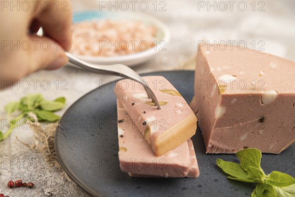 Mortadella sausage with hand on plate with pepper and herbs on brown concrete background and linen textile. Side view, close up, selective focus