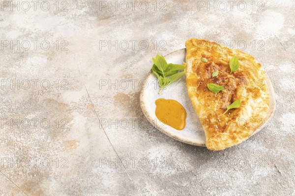 Fried homemade Khachapuri cake with cheese and meat, fried in pan. Traditional Georgian cuisine on brown concrete background. Side view, copy space