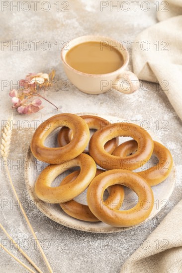 Homemade Ring Bagel with cup of coffee on brown concrete background and linen textile. side view, close up