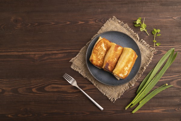 Fried crispy pancakes with meat and cheese on brown wooden background and linen textile. top view, flat lay, copy space