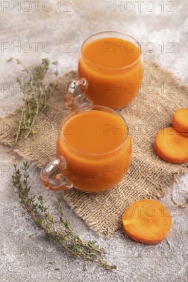 Two glasses with carrot juice, on brown concrete background and linen textile. Diet, healthy eating concept. side view, close up, minimalism