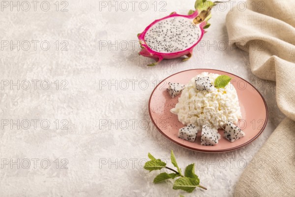 White ?ottage cheese, Curd, with Pithaya on gray concrete background and linen textile, side view, copy space