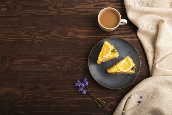 Lemon cake on brown wooden background and linen textile, cup of coffee, top view, flat lay, copy space