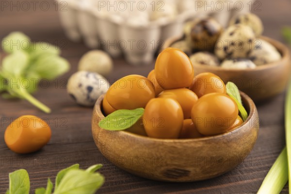Pile of Smoked Quail eggs in bowl on a brown wooden background. side view, close up, selective focus