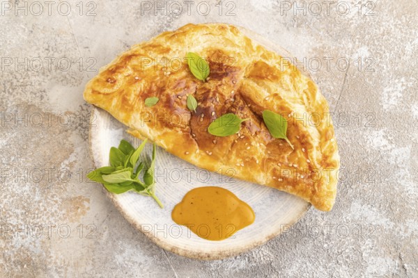 Fried homemade Khachapuri cake with cheese and meat, fried in pan. Traditional Georgian cuisine on brown concrete background. Top view, flat lay, close up