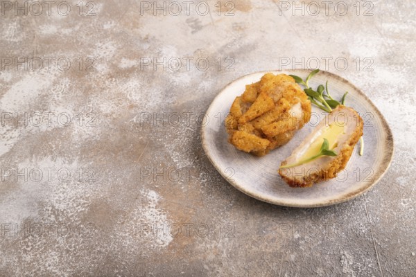 Chicken schnitzel on blue plate with microgreen on brown concrete. Diet, healthy eating. side view, copy space