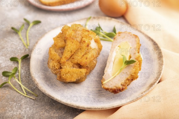Chicken Schnitzel on blue plate with microgreen on brown concrete background and orange linen textile. side view, close up, selective focus