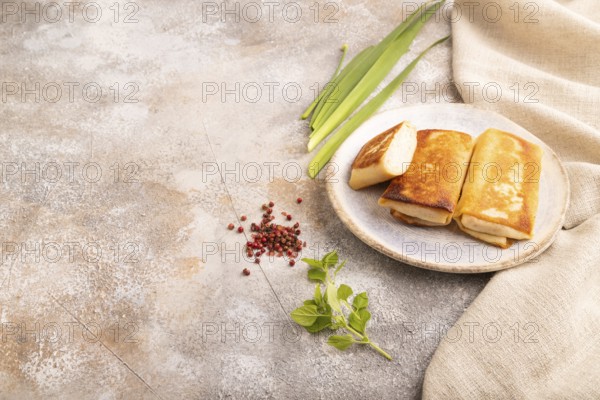 Fried crispy pancakes with meat and cheese on brown concrete background and linen textile. side view, copy space