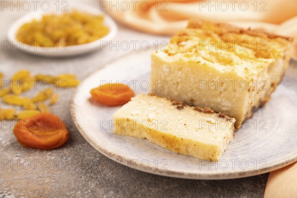 ?ottage cheese ?asserole, Curd cake, with dried apricots and raisins on brown concrete background and orange textile, side view, selective focus, minimalism