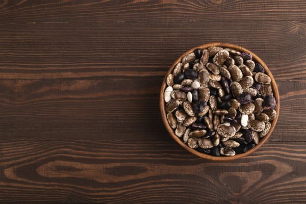 Wooden bowl with Kidney beans on brown wooden background, top view, flat lay, copy space, minimalism