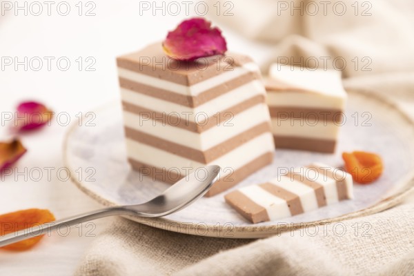 Cocoa and milk jelly with dried apricots on white wooden background and linen textile, side view, close up, minimalism, selective focus