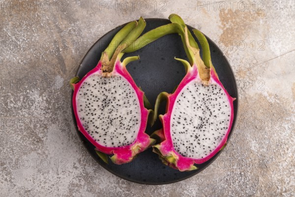 Ripe Pitaya on blue plate on brown concrete background, top view, flat lay, copy space, minimalism