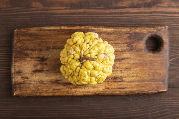 Decorative orange Pumpkin with tumors on cutting board on brown wooden background, top view, flat lay, close up, minimalism