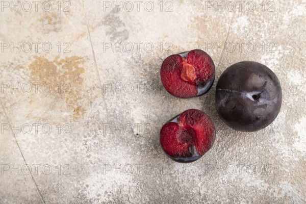 Purple Plum Cut in half on brown concrete background. Top view, flat lay, copy space. healthy food, vegetable, minimalism