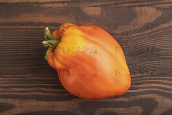 Red Heart Shape tomato on brown wooden background. Top view, flat lay, close up. healthy food, vegetable, minimalism