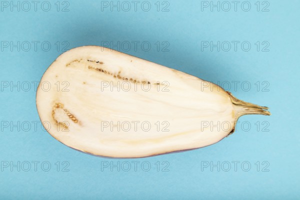 Purple Cutted eggplant with white stripes on blue pastel background. Top view, flat lay, copy space. Tropical, healthy food, vegetable, slice, minimalism