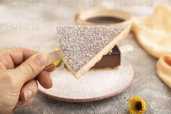 Chocolate and Vanilla Cake pops Marshmallow with hand with cup of coffee on brown concrete background and orange linen textile. side view, close up, selective focus hold