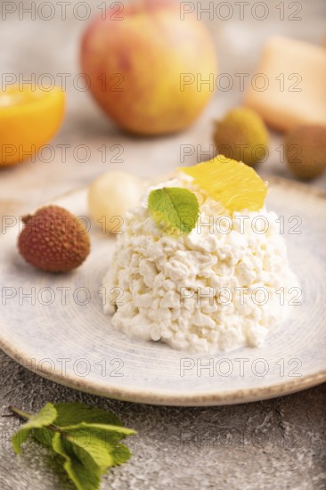 White ?ottage cheese, Curd, with orange and lychee on brown concrete background and orange textile, side view, close up, selective focus