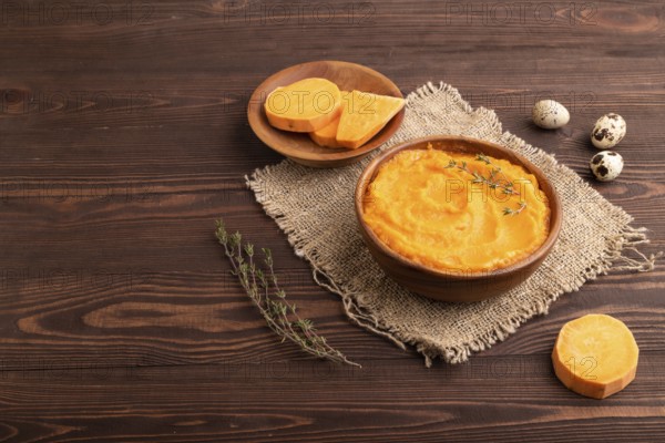 Sweet potato porridge in wooden bowl on wooden background and linen textile. Diet, healthy eating concept. side view, copy space, minimalism