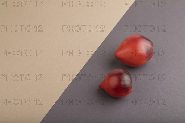 Red Heart shape tomatoes on gray and beige pastel paper background. Side view, copy space. healthy food, vegetable, minimalism